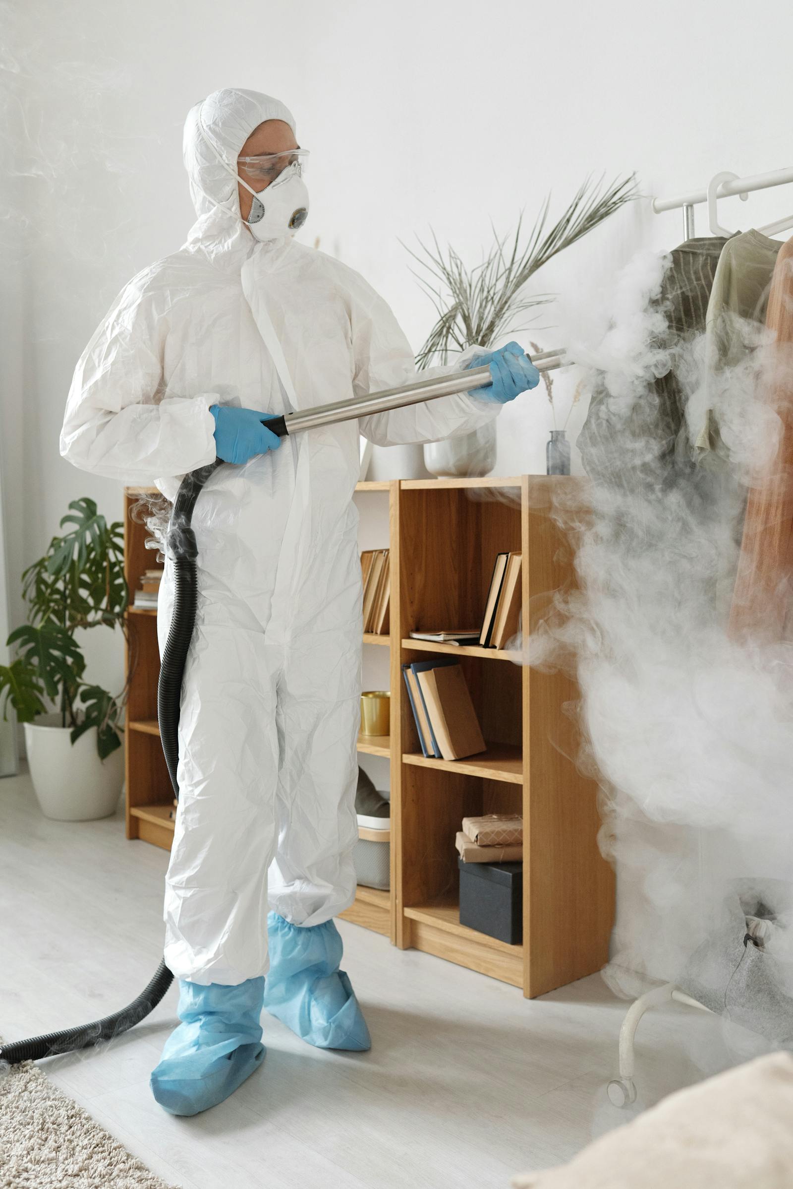 Protective-suit worker disinfecting clothes and nearby surfaces